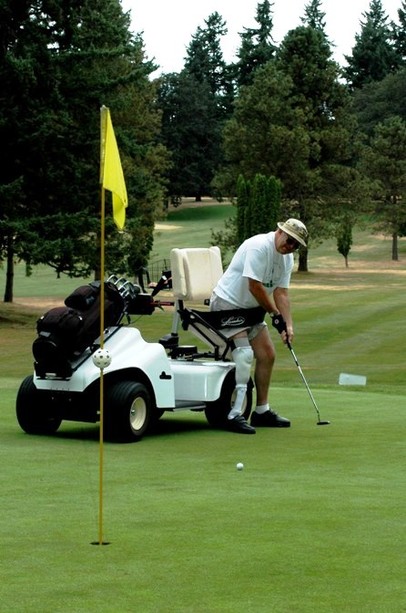 Disabled man using Paragolfer putts on green